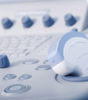 Close-up of an ultrasound machine's control panel and transducer. Smooth, gray and blue buttons suggest a clinical, high-tech medical setting.